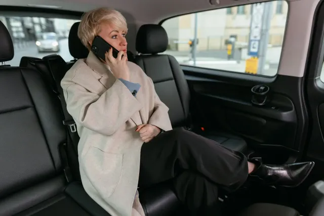 Pasażerka rozmawia przez telefon na tylnej kanapie taksówki w trakcie przejazdu